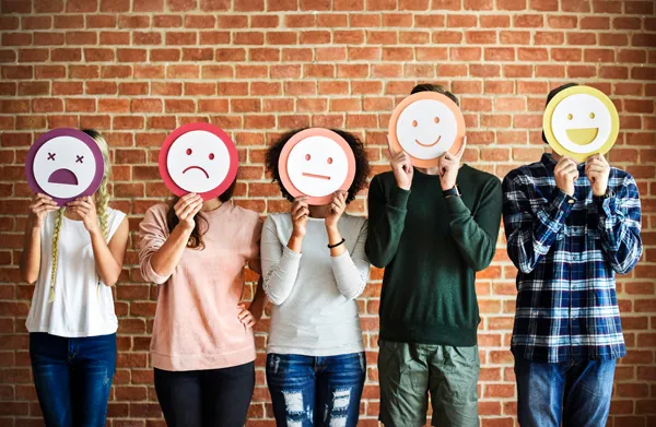 Fotografía de personas sosteniendo ilustraciones de emociones que representa diversidad emocional, expresión humana y acompañamiento consciente