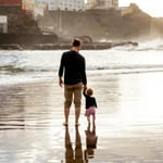 Fotografía de padre e hija caminando en la playa que representa vínculo familiar, acompañamiento emocional y conexión humana